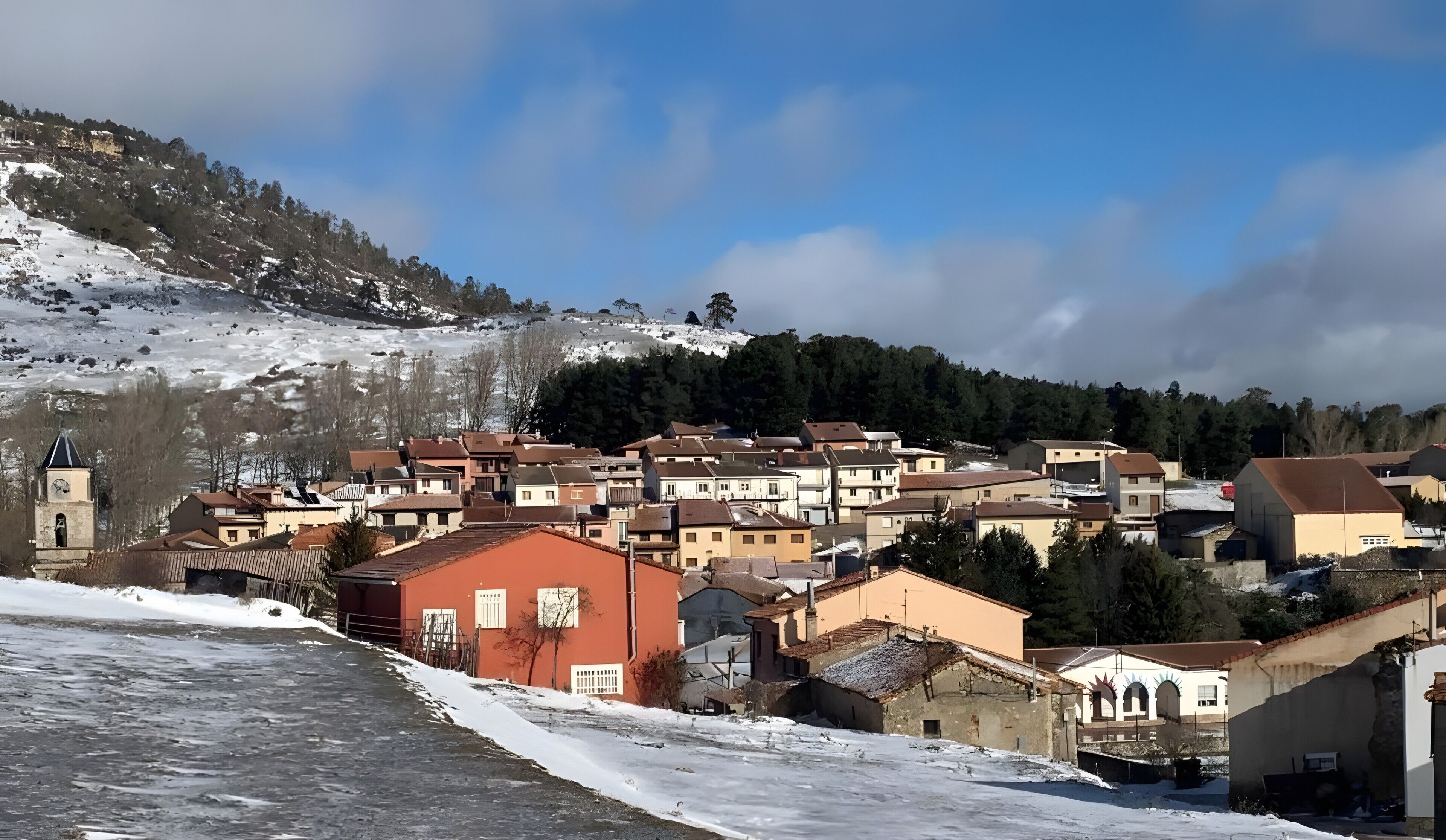 Un village enneigé, avec des bâtiments traditionnels et une église.