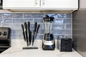 Una encimera de cocina con una licuadora, un tostador y un portalápices.