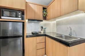 A modern kitchen with stainless steel appliances, wooden cabinets, and a black countertop. - Casanoma by Kozystay - Paskal (Kota Bandung)