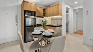 A modern kitchen with built-in appliances, a dining area with a round table and chairs, and a visible plant on the counter. - Casanoma by Kozystay - Paskal (Kota Bandung)