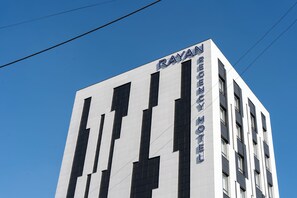 Un edificio moderno con el nombre 'RAYAN RECENCY HOTEL' en su fachada.