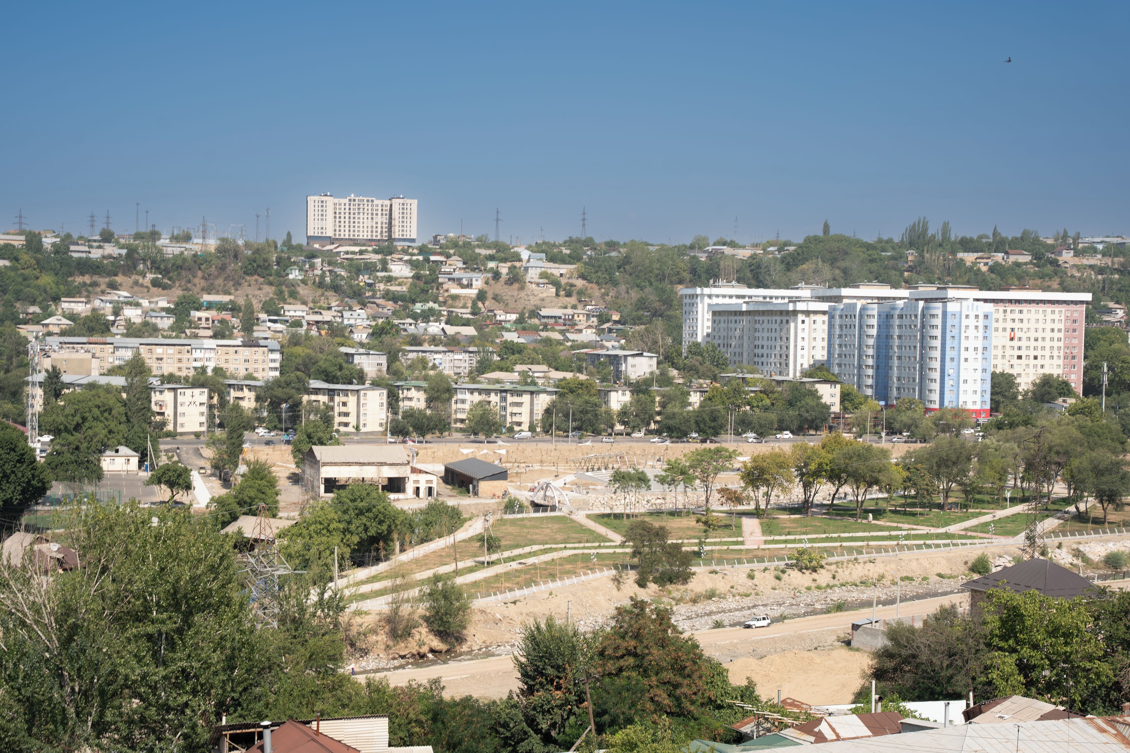 A residential area with multiple apartment buildings, a park with pathways, and a distant view of a larger building.
