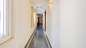 A long, narrow hallway with a dark floor, white walls, and a door at the end. - Townhouse Dwarka Nagar Near Ramatalkies (Visakhapatnam)