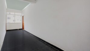 A hallway with a black floor, white walls, and a window at the end. - Collection O Atchutapuram (Visakhapatnam)