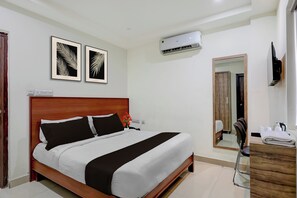 Habitació d'hotel amb un llit, una tauleta de nit, un mirall i un aparell d'aire condicionat.