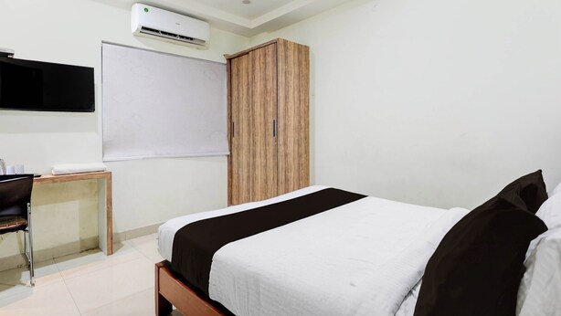 A bedroom with a bed, a wardrobe, a desk with a chair, and an air conditioning unit. - Collection O Atchutapuram (Visakhapatnam)