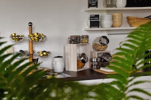 A kitchen counter with various jars, bowls, and utensils. There are shelves above holding more bowls and baskets. - Double Room with Balcony (Braunlage)