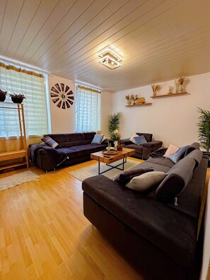 Un salon moderne avec un canapé d’angle, une table basse et une horloge murale décorative.