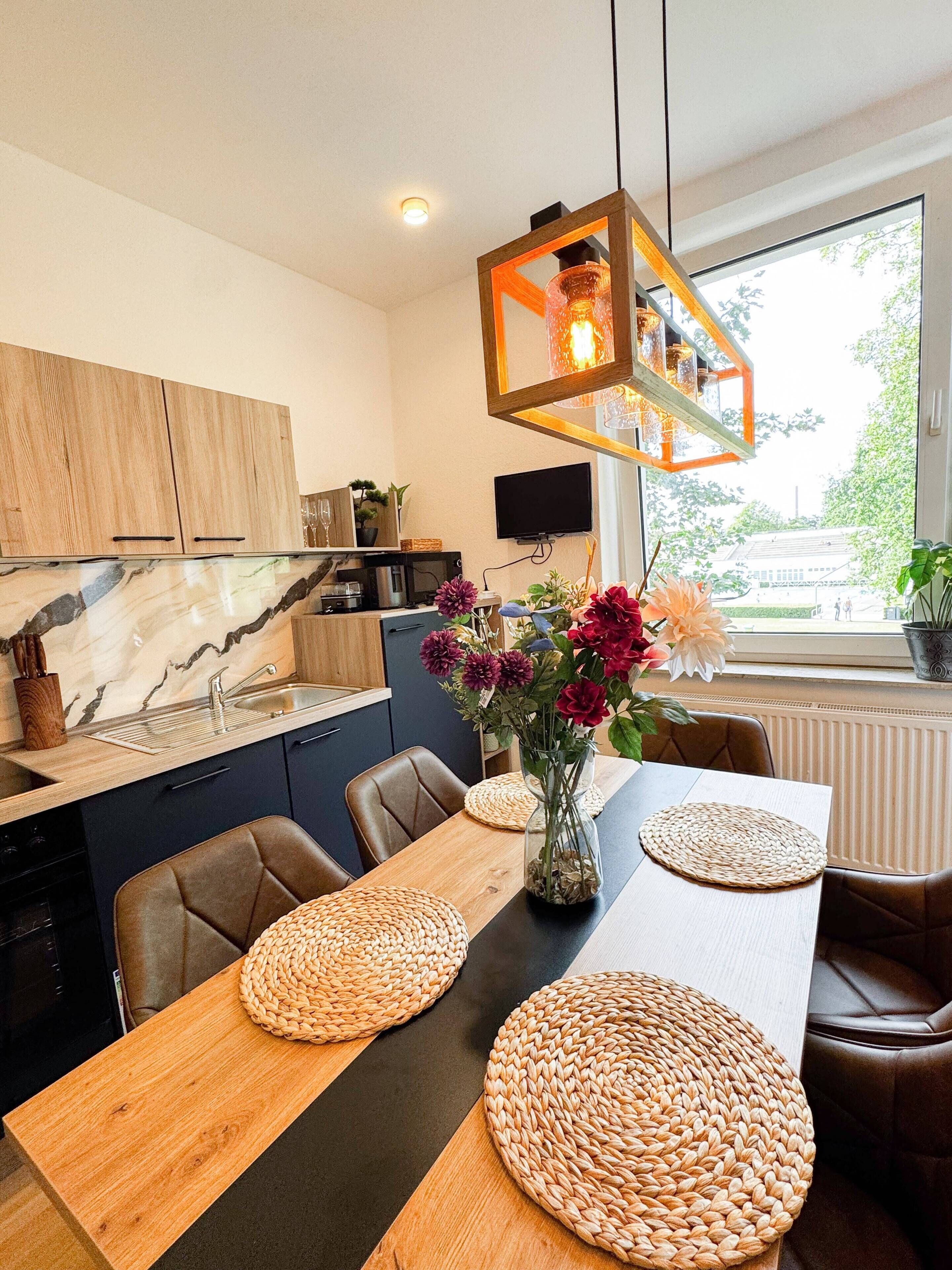 A modern kitchen with wooden cabinets, a marble backsplash, and a dining area with woven placemats.