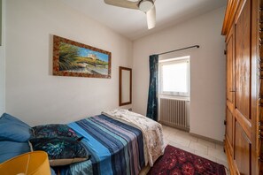 A bedroom with a bed, a window with curtains, a radiator, and a wooden wardrobe. - Casa Serena: with Pine Forest, Jacuzzi Tub & BBQ near the beach, Pet Friendly (San Vito dei Normanni)