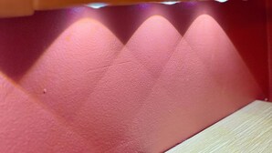 Une étagère sur laquelle sont posés trois mugs roses et un objet rose.