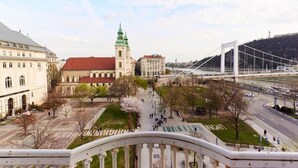 A cityscape with a prominent building with a green roof, a bridge, and a clear sky. - Luxury Riverside Hideaway w/ Panoramic Views & Top Amenities – 622 (Budapest)