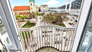 A view from a balcony overlooking a cityscape with a prominent green-roofed building, a white bridge, and a river. - Luxury Riverside Hideaway w/ Panoramic Views & Top Amenities – 622 (Budapest)