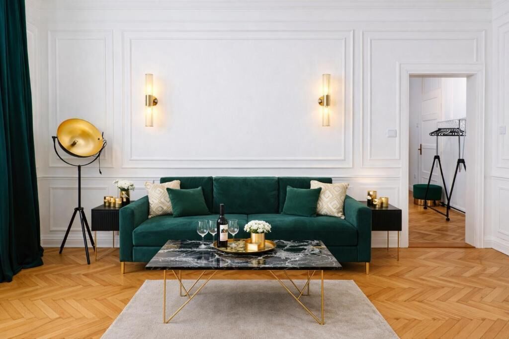A room with a green sofa, a marble coffee table, and a floor lamp.
