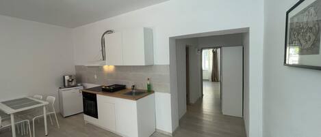 Cocina compacta con zona de comedor, cafetera y pileta.