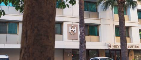 Un hotel con un cartel que dice 'Heights Suites' y otro cartel que indica 'Residencias'. Palmeras en la parte frontal del edificio.