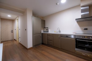 A modern kitchen with stainless steel appliances, wooden flooring, and a built-in oven.