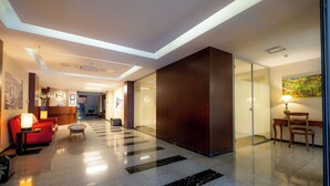 A modern hotel lobby with a reception desk, seating area, and a glass partition wall. - Heykel Suites (Konak)