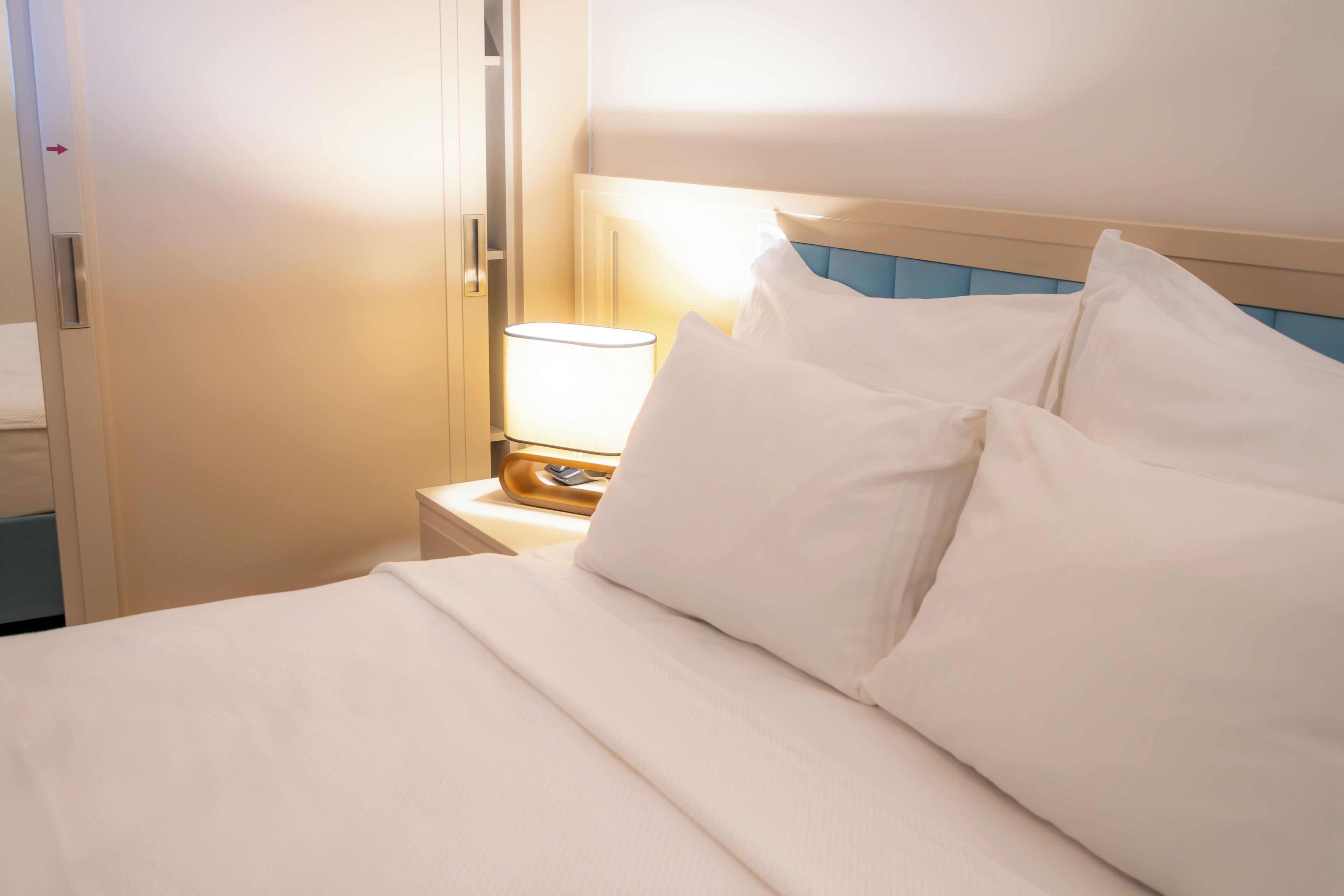 A hotel room with a bed, a nightstand, and a lamp.
