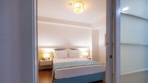 A bedroom with a bed, bedside lamps, and a nightstand. - Heykel Suites (Konak)