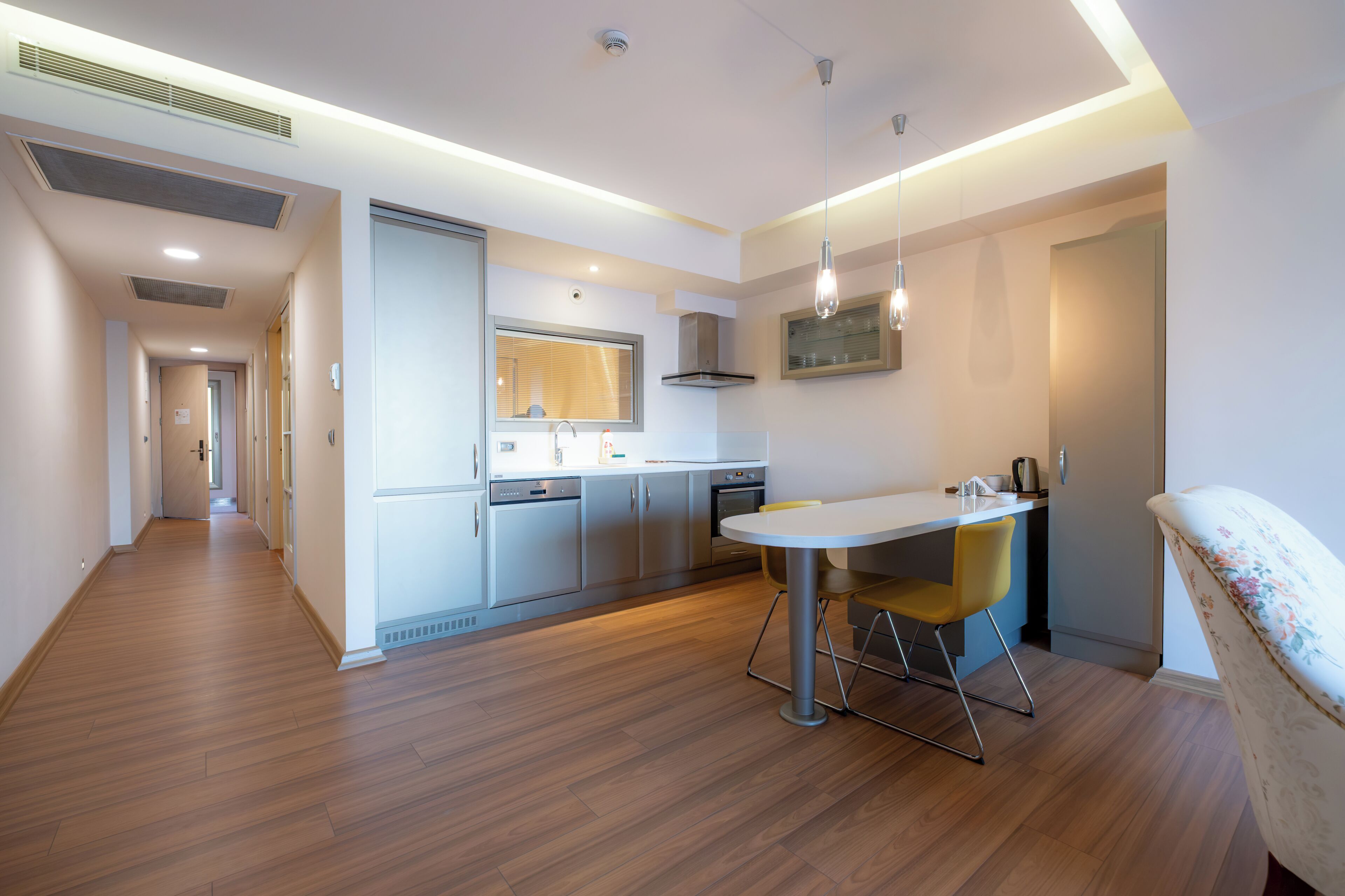 Una cocina moderna con comedor, suelo de madera y vistas al pasillo.