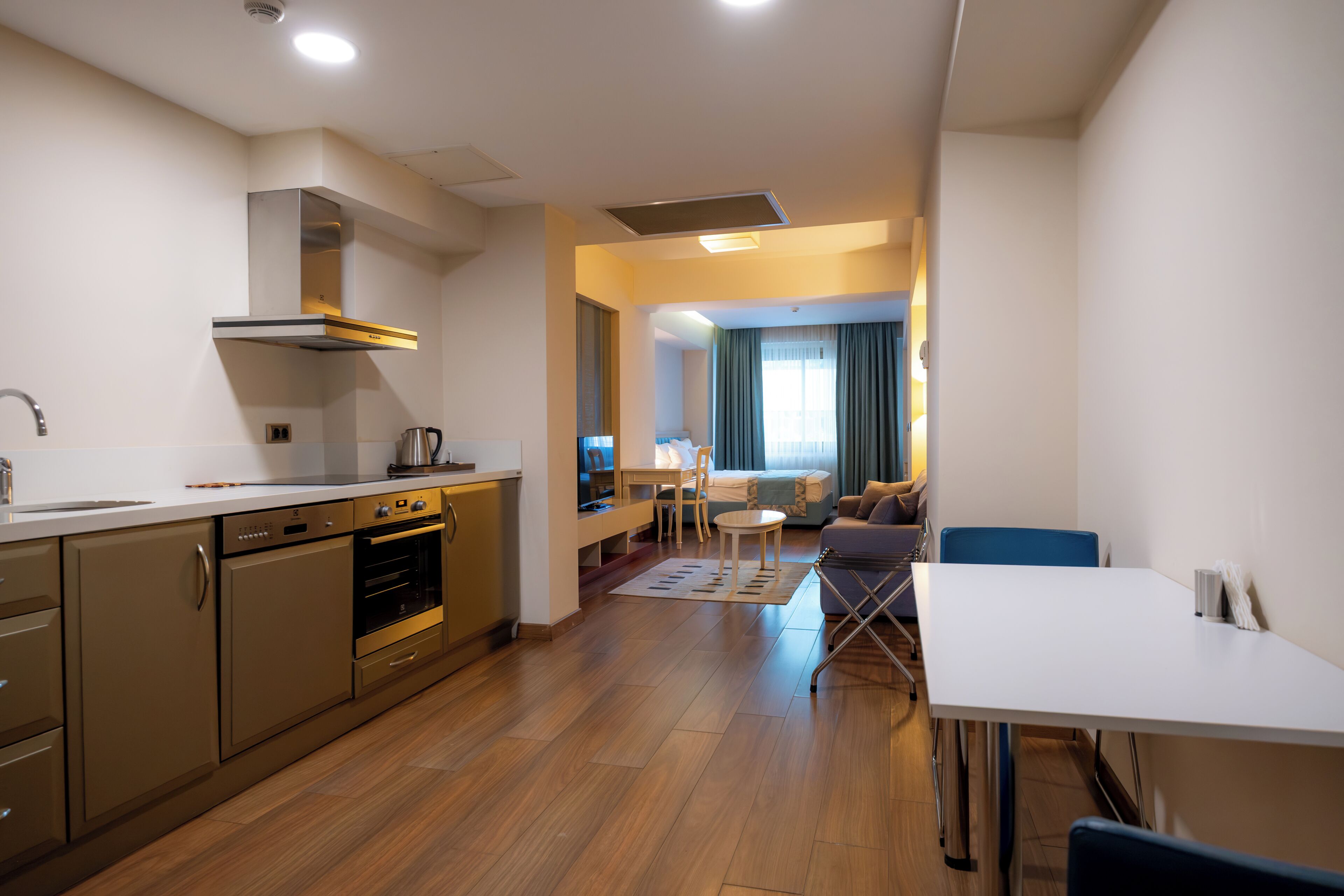A modern kitchen with built-in appliances, a dining area with a table and chairs, and a living space with a sofa and a TV.