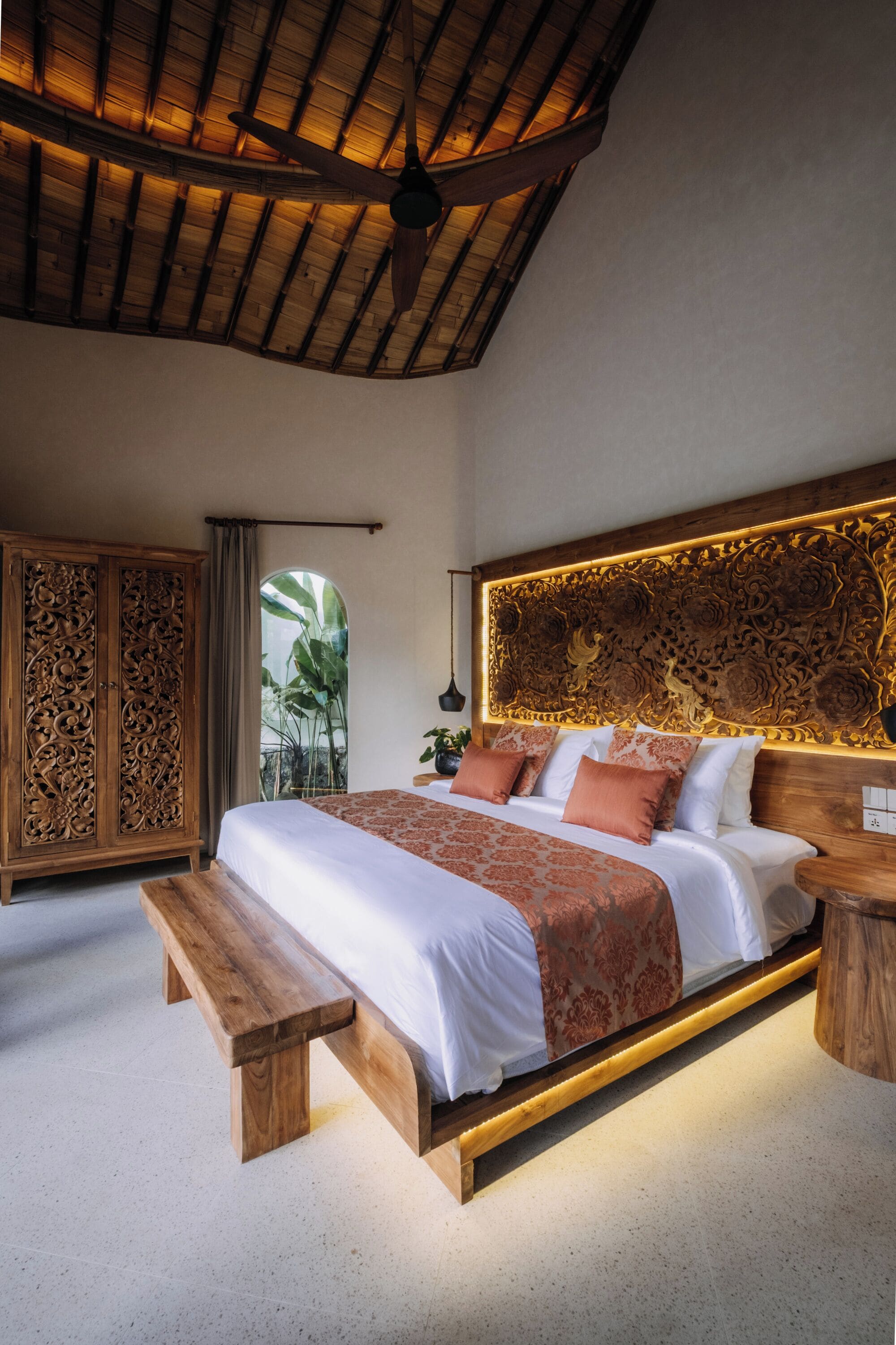 A bedroom with a large bed, wooden headboard, and a ceiling fan.