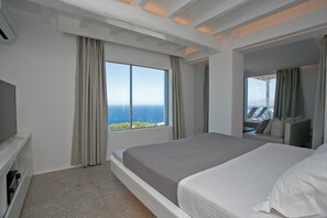 Une chambre d’hôtel moderne avec un grand lit, une télévision et une vue sur l’océan.
