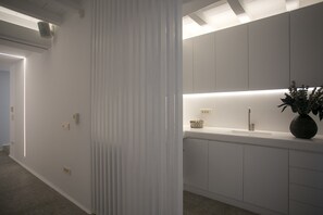 Une cuisine moderne avec des meubles blancs, un four encastré et un plan de travail agrémenté d’un vase de fleurs.
