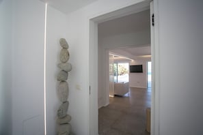 Ein Flur mit einer Wandinstallation aus Stein, einer Tür zu einem Raum mit großem Fenster und einem modernen Interieur.