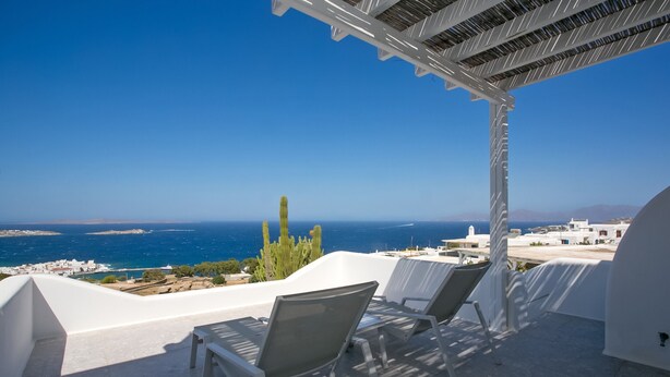 Une terrasse avec des chaises blanches et une vue sur la mer.