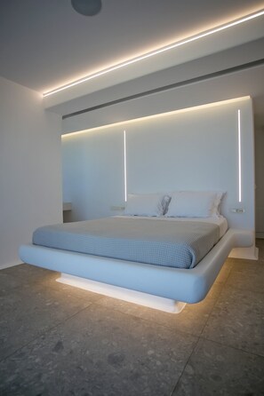 A modern bedroom with a large bed, recessed lighting, and a minimalist design. - Mykonos Seabreeze Town Villa (Mykonos)