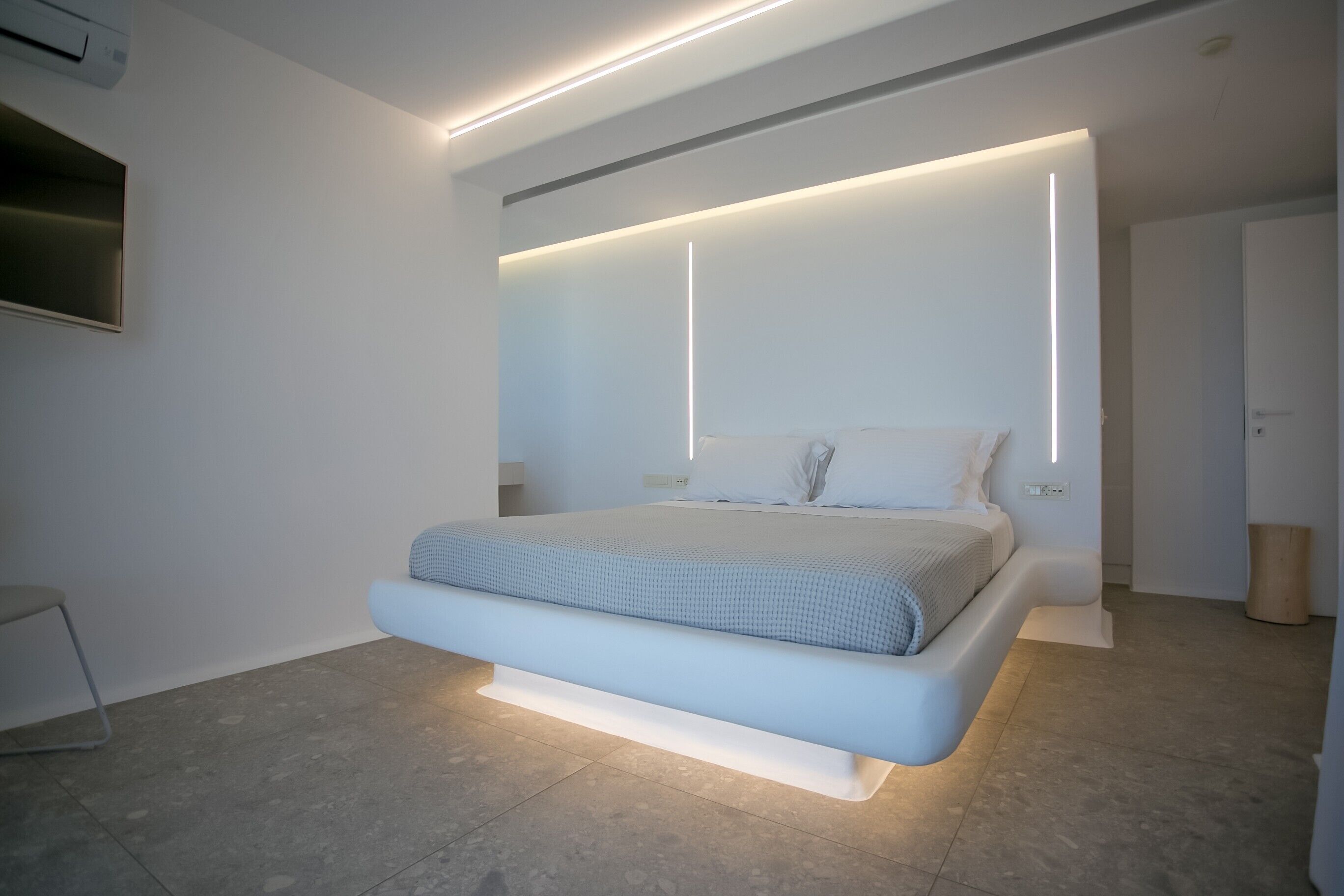 Un dormitorio moderno con una cama centrada bajo un amplio panel de pared iluminado.