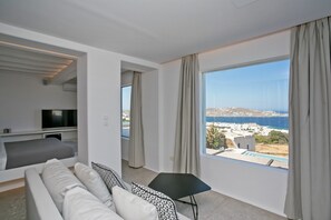 A modern hotel room with a large window offering a view of the sea and a cityscape. - Mykonos Seabreeze Town Villa (Mykonos)