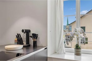 A kitchen counter with a coffee maker, utensils, and a plate. - Designer Old Town Residence | WaterView | AC (Zürich)