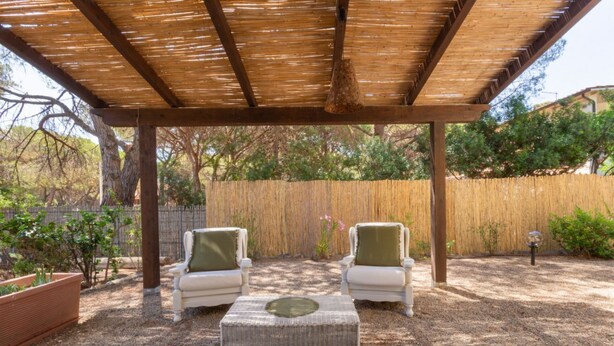 A covered outdoor seating area with two white chairs and a wicker ottoman. - Villa Grazia – Your relaxing escape just steps from the sea 🌿☀️ (Santa Margherita di Pula)