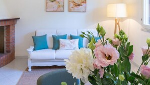 A living room with a white sofa, teal cushions, a fireplace, and a lamp. - Villa Grazia – Your relaxing escape just steps from the sea 🌿☀️ (Santa Margherita di Pula)