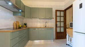 A kitchen with green cabinets, a stainless steel range hood, a sink, and a wooden countertop. - Villa Grazia – Your relaxing escape just steps from the sea 🌿☀️ (Santa Margherita di Pula)