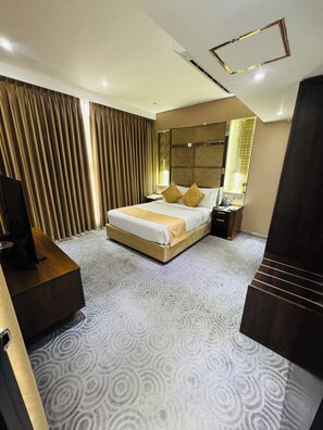 A hotel room with a large bed, a bedside table, a mirror, and a wardrobe. - Unique Regency Hotel (Dhaka)