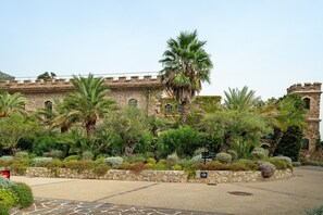 Un cortile con un edificio in pietra, palme e un viale lastricato.