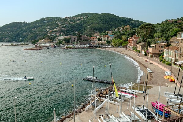 Un pueblo costero con un puerto deportivo, barcos y una playa de arena.