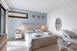 Un dormitorio con cama, mesitas de noche, espejo, silla y mesa de centro.