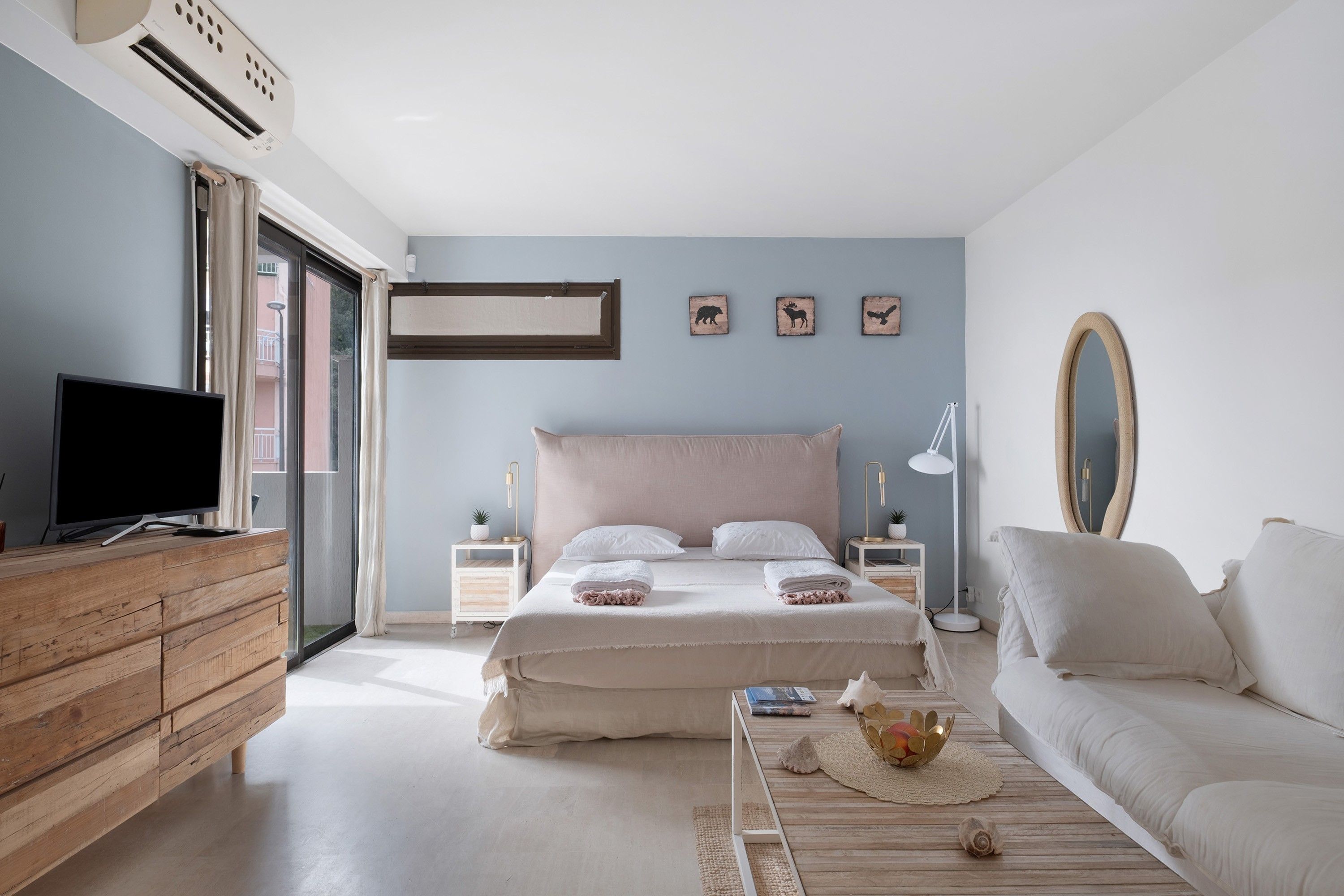Une chambre à coucher avec un lit, une télévision, un canapé et une fenêtre avec des rideaux.