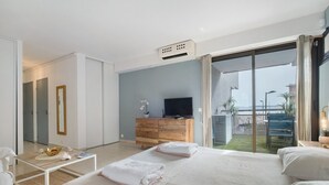 Et moderne hotelværelse med en stor seng, fjernsyn, et trækommode og havudsigt.