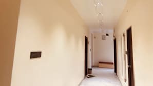 A hallway with doors on both sides, a bench in the center, and a ceiling with recessed lighting. - Hotel Agrawal Inn (Ujjain)