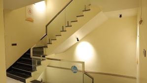 A staircase with glass railings and a handrail, leading to an upper floor. - Hotel Agrawal Inn (Ujjain)