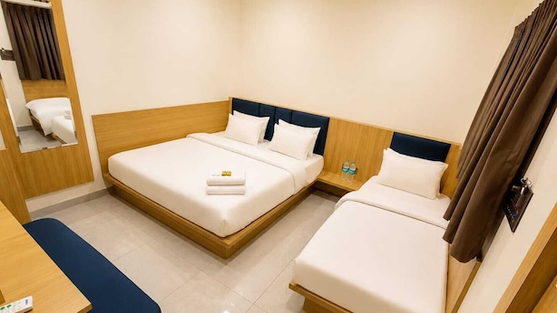 A hotel room with two beds, a desk, a chair, and a mirror. - Hotel Agrawal Inn (Ujjain)