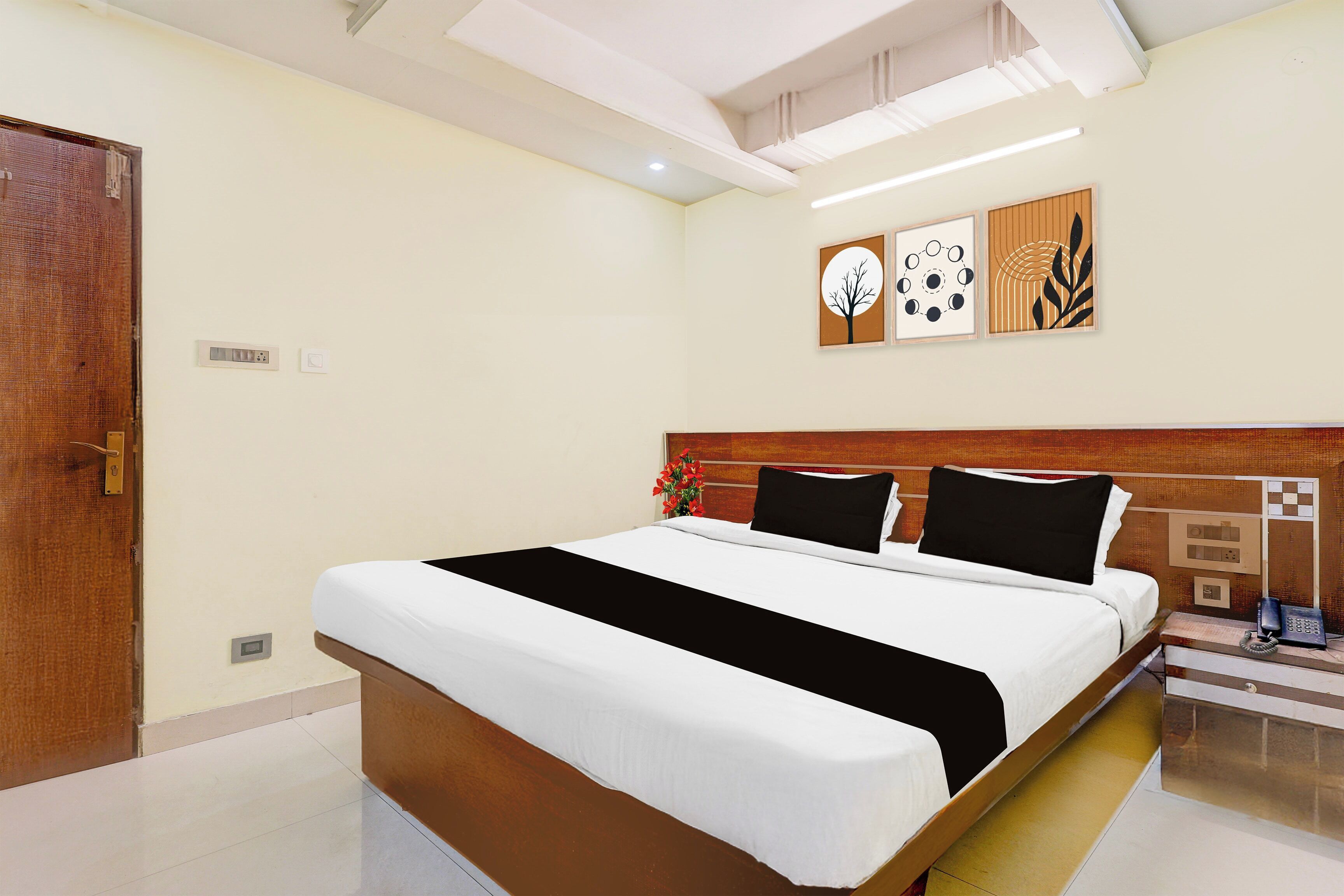 A hotel room with a large bed, a wooden headboard, a bedside telephone, and a wall-mounted light fixture.