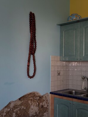 A kitchen with teal cabinets, a tiled backsplash, and a hanging wooden object. - Apartment Just a Stone's Throw from the Sea (Santa Maria di Castellabate)