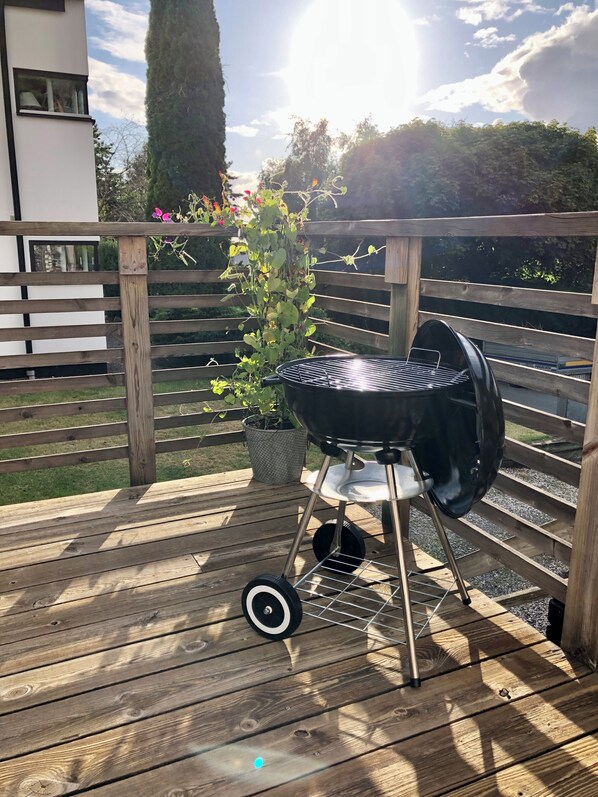 A wooden deck with a barbecue grill, a potted plant, and a wooden fence.